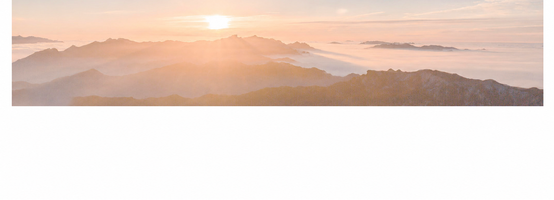 Sunrise over a mountain range with soft pink and orange hues.